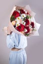 A woman is holding a bouquet of gerbera flowers. The florist creates a red beautiful bouquet of mixed flowers.