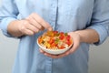 Woman holding bowl of colorful jelly bears on light background