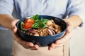 Woman holding bowl of delicious buckwheat porridge with vegetables and mushrooms