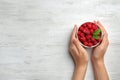 Woman holding bowl with delicious ripe raspberries at white wooden table. Space for text Royalty Free Stock Photo