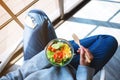 A woman holding a bowl of fresh mixed vegetables salad while sitting on the a chair Royalty Free Stock Photo