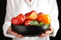 Woman holding bowl with fresh ripe tomatoes on black background, closeup Royalty Free Stock Photo