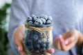 Woman holding bowl with Frozen blueberry fruits. Harvesting concept. Female hands collecting berries. Healthy eating