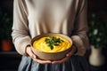 Woman holding a bowl with pumpkin cream soup. Autumn hygge cozy dinner concept