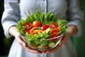 Woman holding a bowl of salad, with vibrant fresh vegetables and a low calories dressing. Concept healthy nutritious meal.