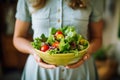 Woman holding a bowl of salad, with vibrant fresh vegetables and a low calories dressing. Concept healthy nutritious meal.