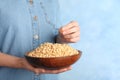 Woman holding bowl with shelled pine nuts on color background Royalty Free Stock Photo