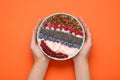 Woman holding bowl of tasty smoothie with fresh berries and granola on orange background, top view Royalty Free Stock Photo