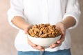 Woman holding bowl with tasty walnuts