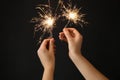 Woman holding bright burning sparklers on black background, closeup Royalty Free Stock Photo