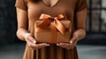 A woman holding a brown gift box with orange ribbon, AI Royalty Free Stock Photo