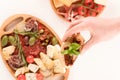 Woman holding bruschetta with sun-dried tomatoes above the white table served with traditional Italian antipasti