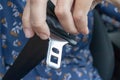 Woman holding a buckle of a safety belt in hand and fastening a seatbelt, car safety and driver protection concept