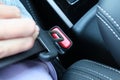 Woman holding a buckle of a safety belt in hand and fastening a seatbelt, car safety and driver protection concept