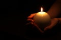 Woman holding burning candle in hands on black background, closeup. Space for text Royalty Free Stock Photo