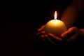 Woman holding burning candle in hands on black background, closeup. Space for text Royalty Free Stock Photo