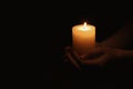 Woman holding burning candle in hands on black background, closeup. Space for text Royalty Free Stock Photo