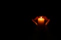 Woman holding burning candle in hands on black background, closeup. Space for text Royalty Free Stock Photo