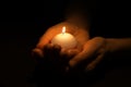 Woman holding burning candle in hands on black background, closeup Royalty Free Stock Photo