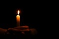 Woman holding burning candle in hands on black background. Space for text Royalty Free Stock Photo