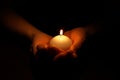 Woman holding burning candle in hands on black background Royalty Free Stock Photo