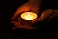 Woman holding burning candle in hands on black background, closeup Royalty Free Stock Photo