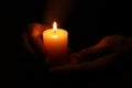 Woman holding burning candle in hands on black background, closeup Royalty Free Stock Photo