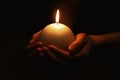 Woman holding burning candle in hands on black background, closeup Royalty Free Stock Photo