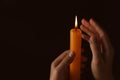 Woman holding burning church candle on black background, closeup. Space for text