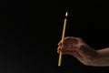 Woman holding burning church candle on black background, closeup