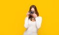 Woman holding camera over yellow background. Girl using a camera photo. Photographer camera photo, photographing girl Royalty Free Stock Photo