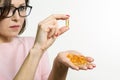 Woman holding capsule with vitamin E, fish oil, Omega 3. White background, isolated, focus on the capsule Royalty Free Stock Photo