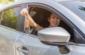 Woman holding a car key in her hand while sitting in her car. Royalty Free Stock Photo