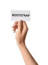 Woman holding card with word BOOTSTRAP on background, closeup