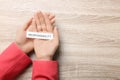 Woman holding card with word Responsibility at wooden table top view