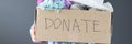 Woman holding cardboard box with donations in her hand closeup