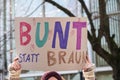 Woman holding a cardboard sign with the German text Bunt statt Braun (Colorful instead of Brown), protest against racism