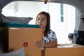 Woman holding and carrying a cardboard box with stuffs moving into the car to relocation on moving day.