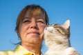 Woman holding cat on blue sky background outdoors. Royalty Free Stock Photo