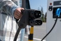 Woman holding CCS fast charging socket type 2 plug for electric vehicles at EV car charging station. Royalty Free Stock Photo