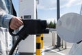 Woman holding CCS fast charging socket type 2 plug for electric vehicles at EV car charging station. Royalty Free Stock Photo