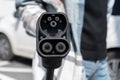 Woman holding CCS fast charging socket type 2 plug for electric vehicles at EV car charging station. Royalty Free Stock Photo