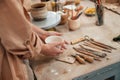 Woman holding ceramic pot in hands. Table with tools. Close up view