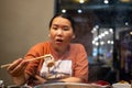 Woman holding chopsticks with a piece of meat in restaurant