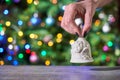 Woman holding Christmas bell, Christmas lights in the background. Royalty Free Stock Photo