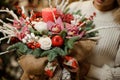 Woman holding a christmas composition with pink orchids, white roses, fir-tree branches, red apple and candle in the Royalty Free Stock Photo