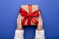 Woman holding Christmas gift box wrapped in craft paper on color background. Female hands holding present for Christmas Royalty Free Stock Photo