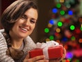 Woman holding christmas present box in front of christmas tree Royalty Free Stock Photo