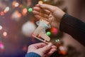 Woman holding christmas tree wooden toy in her hands and hanging it on the Christmas fir tree. Winter holidays lights and garlands Royalty Free Stock Photo