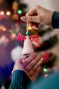 Woman holding christmas tree wooden toy in her hands and hanging it on the Christmas fir tree. Winter holidays lights and garlands Royalty Free Stock Photo